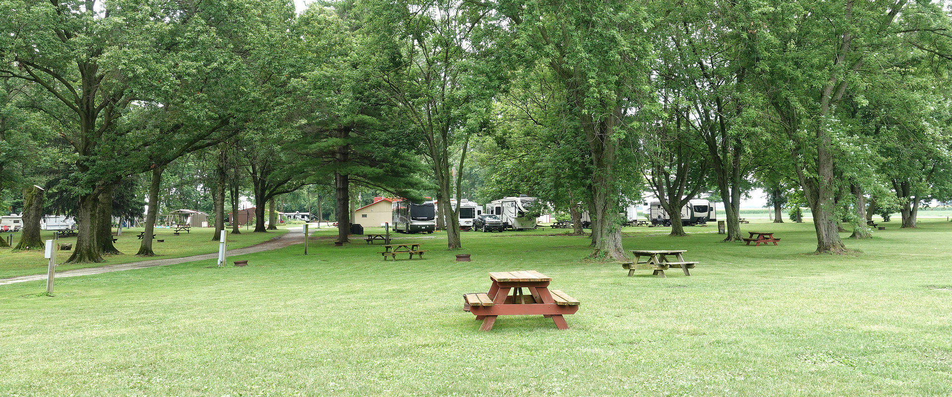 Field with picnic tables and RVs in background